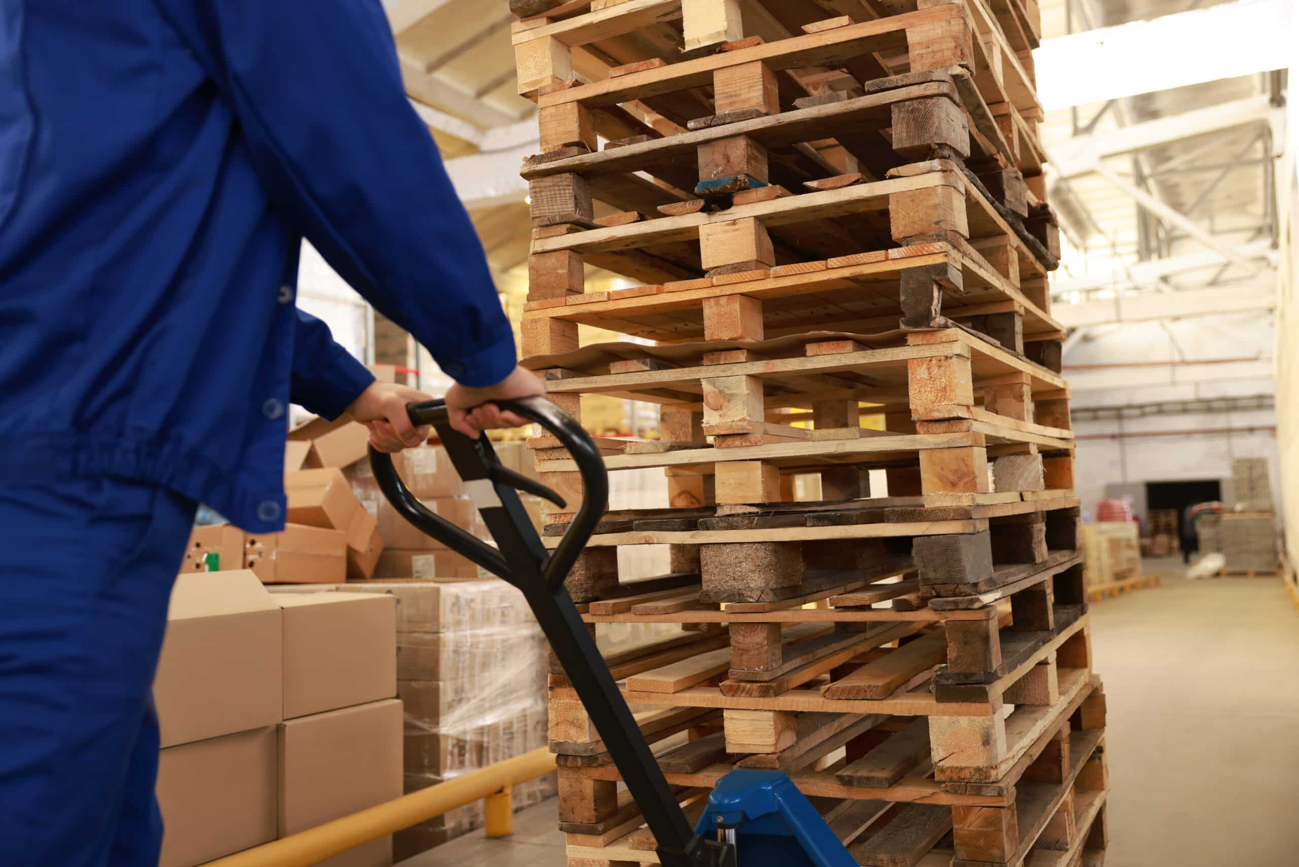 warehouse worker moving a pile of pallets using hand pallet truck
